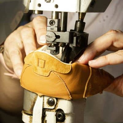 Artigiana che sta cucendo la tomaia di una scarpa primi passi Barberini. Scarpe fatte artigianalmente a mano in Italia. Made in Italy