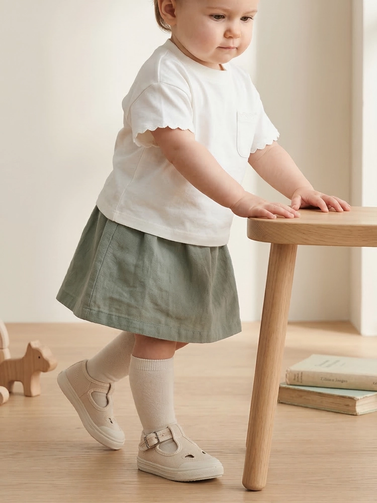 Una bambina che esplora l'ambiente indossando le scarpine Talpa beige.