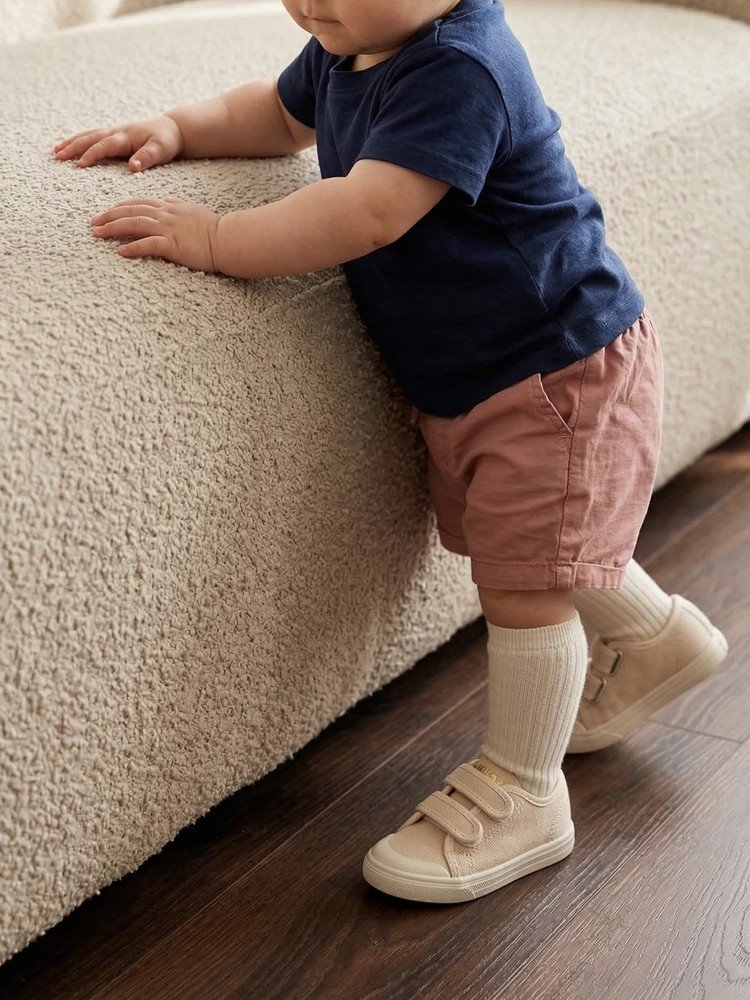 Bambino che esplora l'ambiente indossando le scarpine Dondi beige.