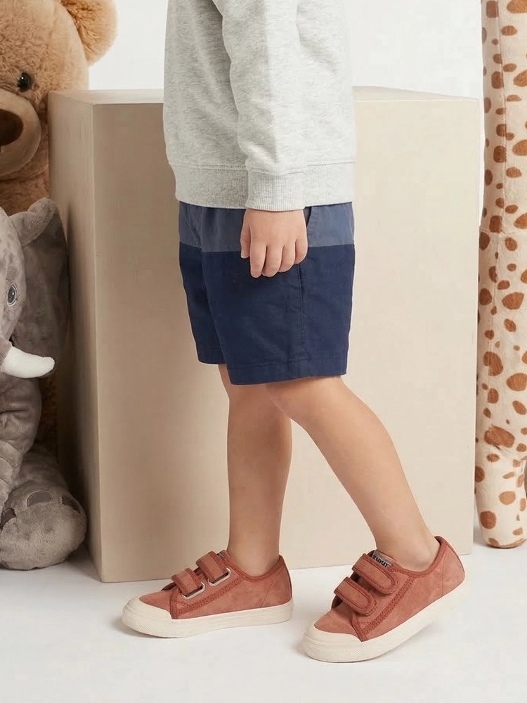 Un bambino che esplora l'esterno indossando scarpine estive per bambini.