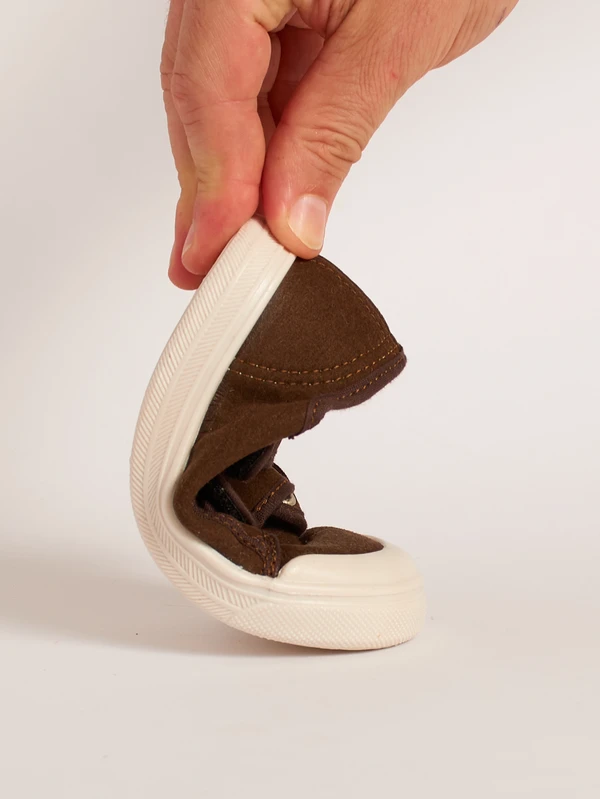 Dimostrazione della flessibilità e piegatura anatomica della suola drop zero nella scarpa primi passi classica marrone