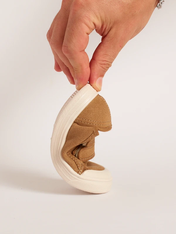 Dimostrazione della flessibilità e piegatura anatomica della suola drop zero nelle scarpe primi passi classiche marrone chiaro